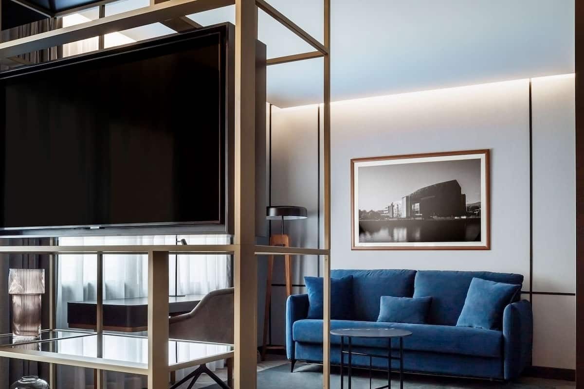 A modern living room with a TV, blue sofa, and a framed picture on the wall.