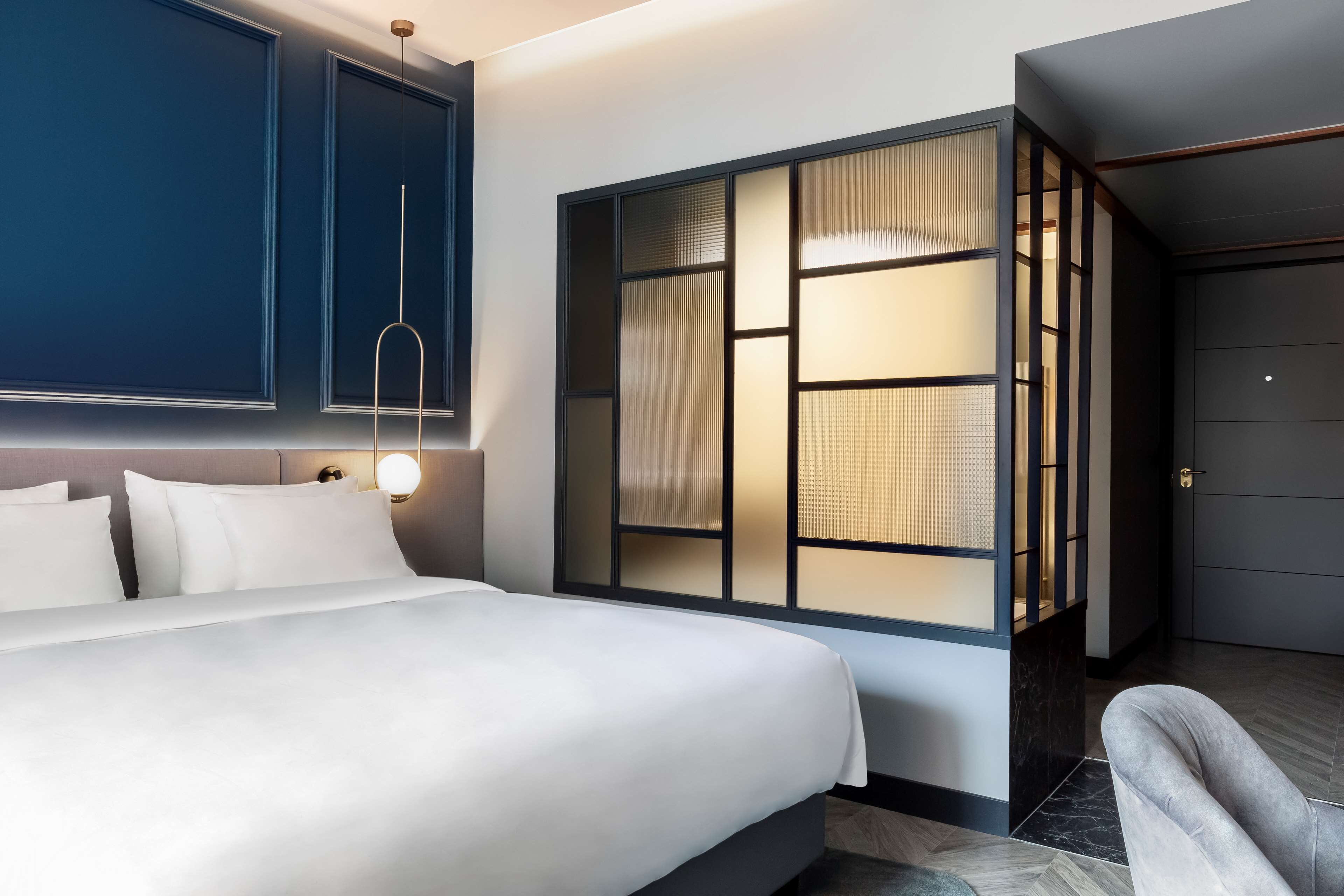 Una habitación de hotel moderna con una cama grande, un televisor montado en la pared y una puerta corredera con vistas.