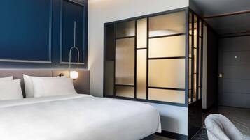 Una habitación de hotel moderna con una cama grande, un televisor montado en la pared y una puerta corredera con vistas.