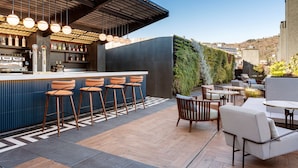 A modern outdoor bar area with a counter, bar stools, and seating. - Radisson Collection Bilbao (Bilbao)