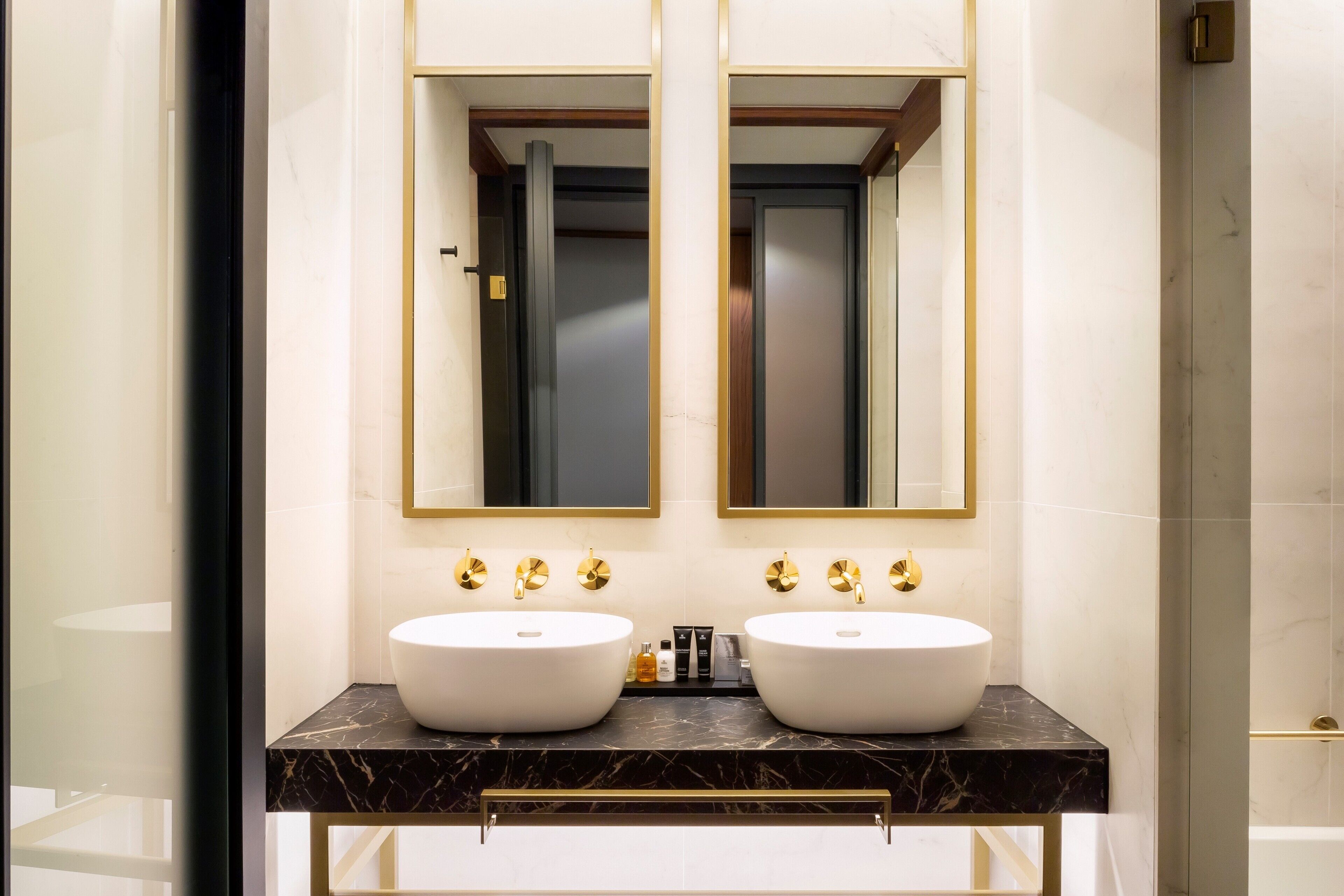 Un baño con dos lavamanos, un espejo y una puerta.