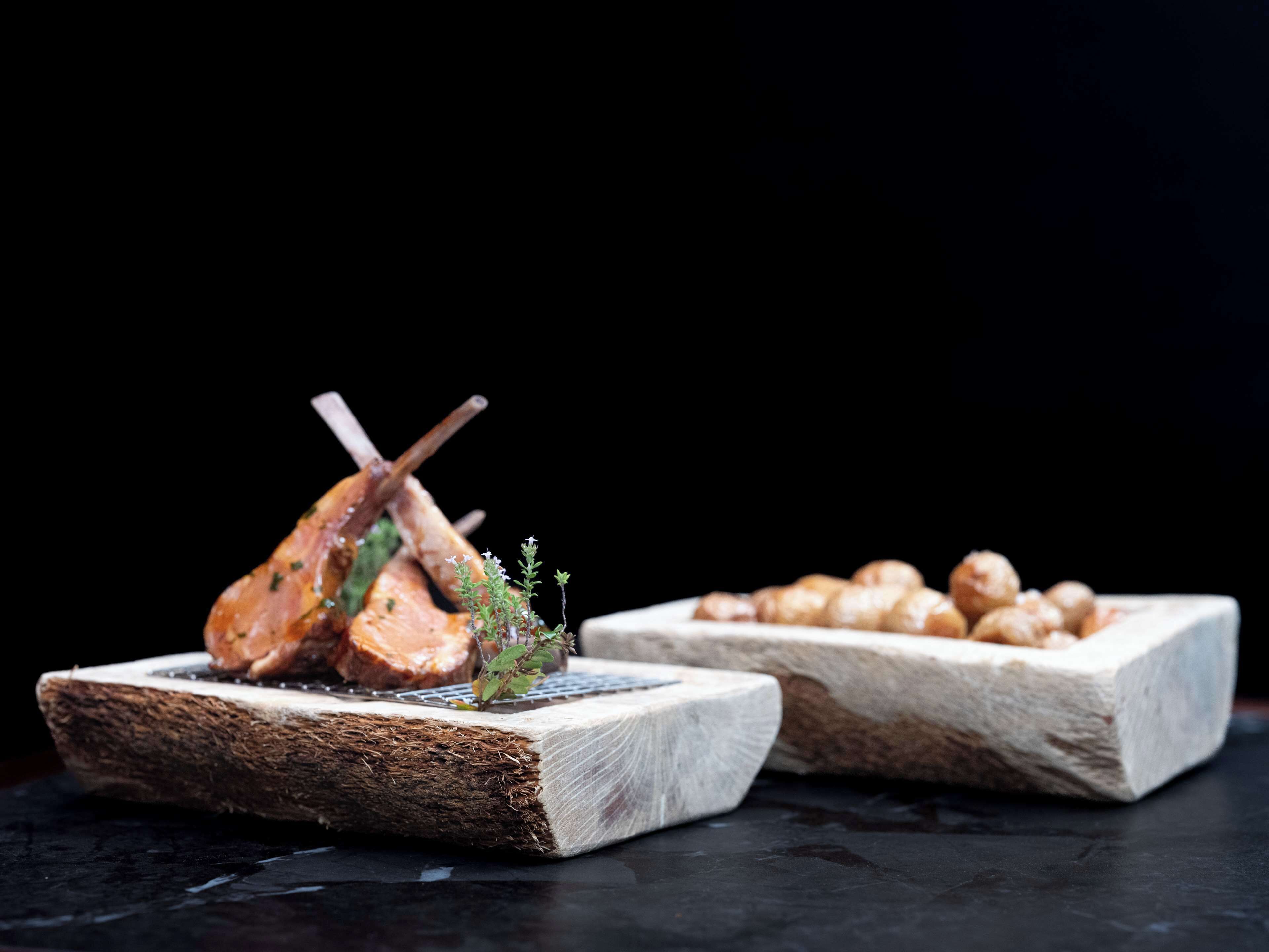 Una tabla de madera con un lechón asado y una pequeña guarnición de hierbas.