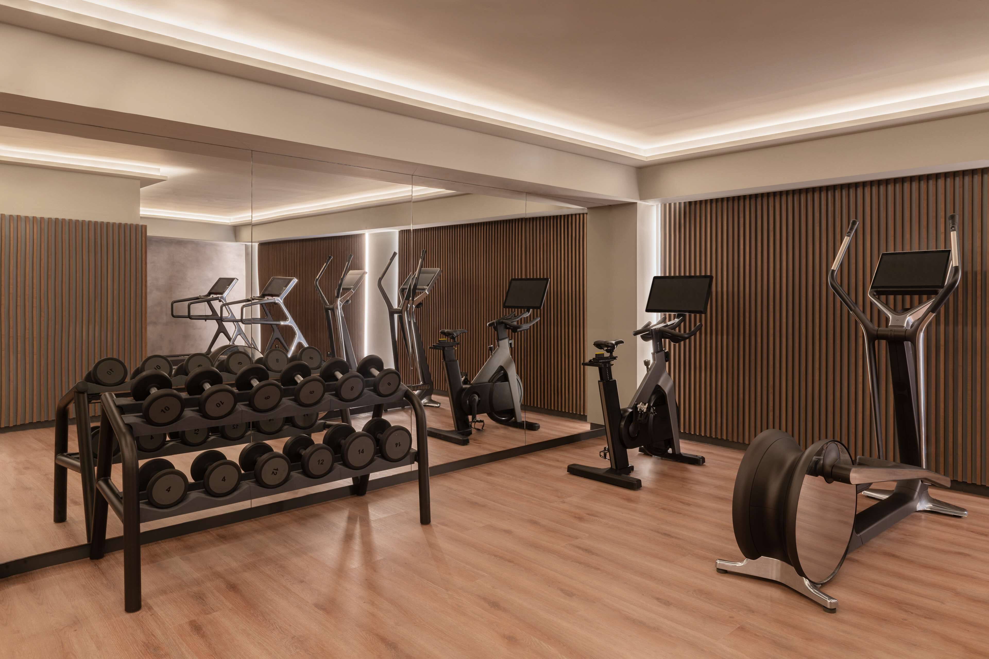 A modern gym with exercise equipment and a mirrored wall.