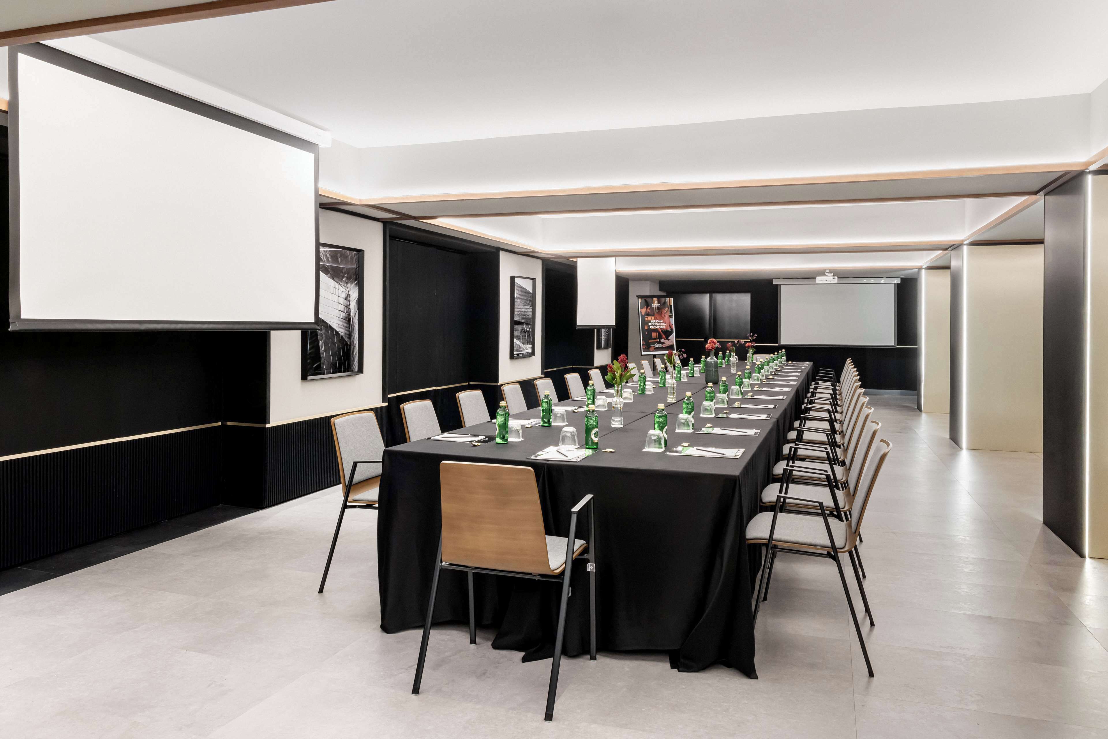 A conference room with a long table, chairs, and a projector screen.