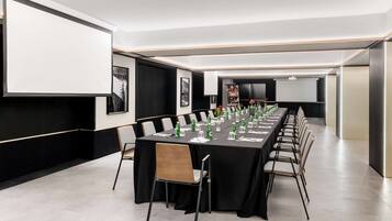 A conference room with a long table, chairs, and a projector screen.