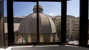 Una ventana de esquina con vistas a un edificio que tiene una cúpula grande y una torre más pequeña.