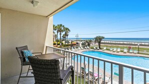 A balcony with a view of a pool and the ocean.