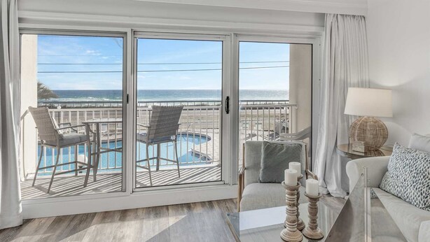 A hotel room with a balcony, a pool, and a view of the ocean.