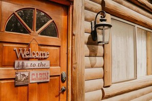 Una puerta de cabaña de madera con un cartel de bienvenida, un letrero de cabaña y una cerradura electrónica.