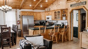 L’intérieur d’une cabane comprend un coin repas, une cuisine et un espace de vie avec un canapé et des fauteuils.