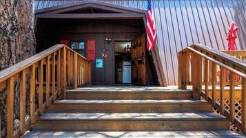 A wooden staircase leading to a cabin entrance with an American flag on the right.