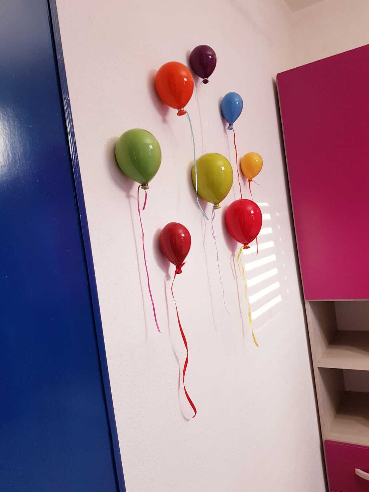 A white wall with balloons in various colors.