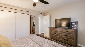 Ein Schlafzimmer mit Bett, Kommode, Fernseher und Schrank.