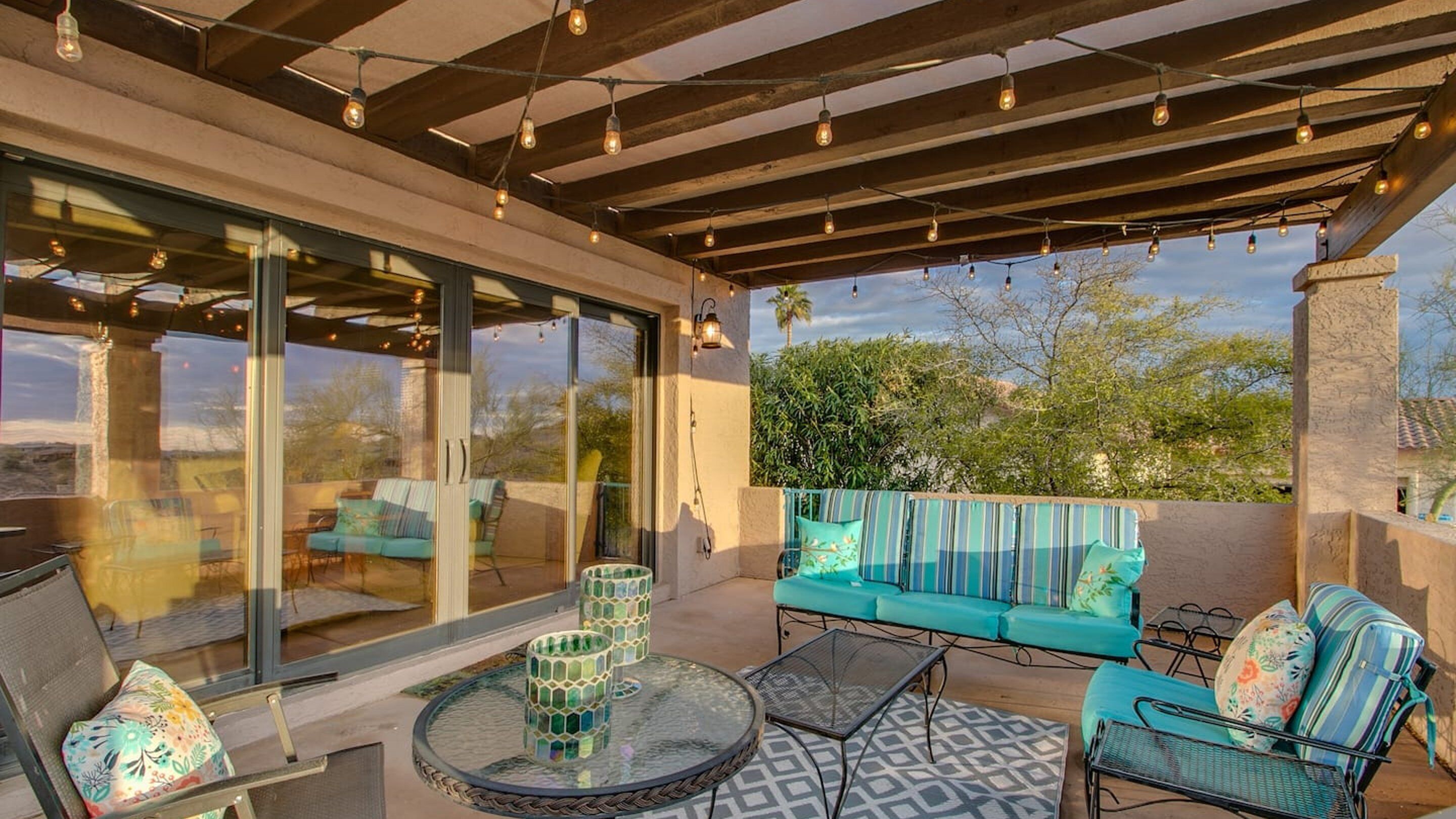 An outdoor patio with a glass enclosure, a sofa set, and a round table.