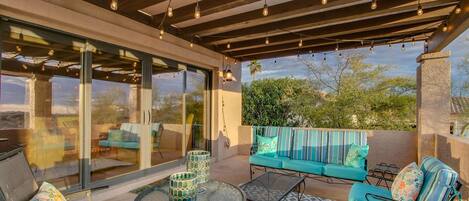 An outdoor patio with a glass enclosure, a sofa set, and a round table.