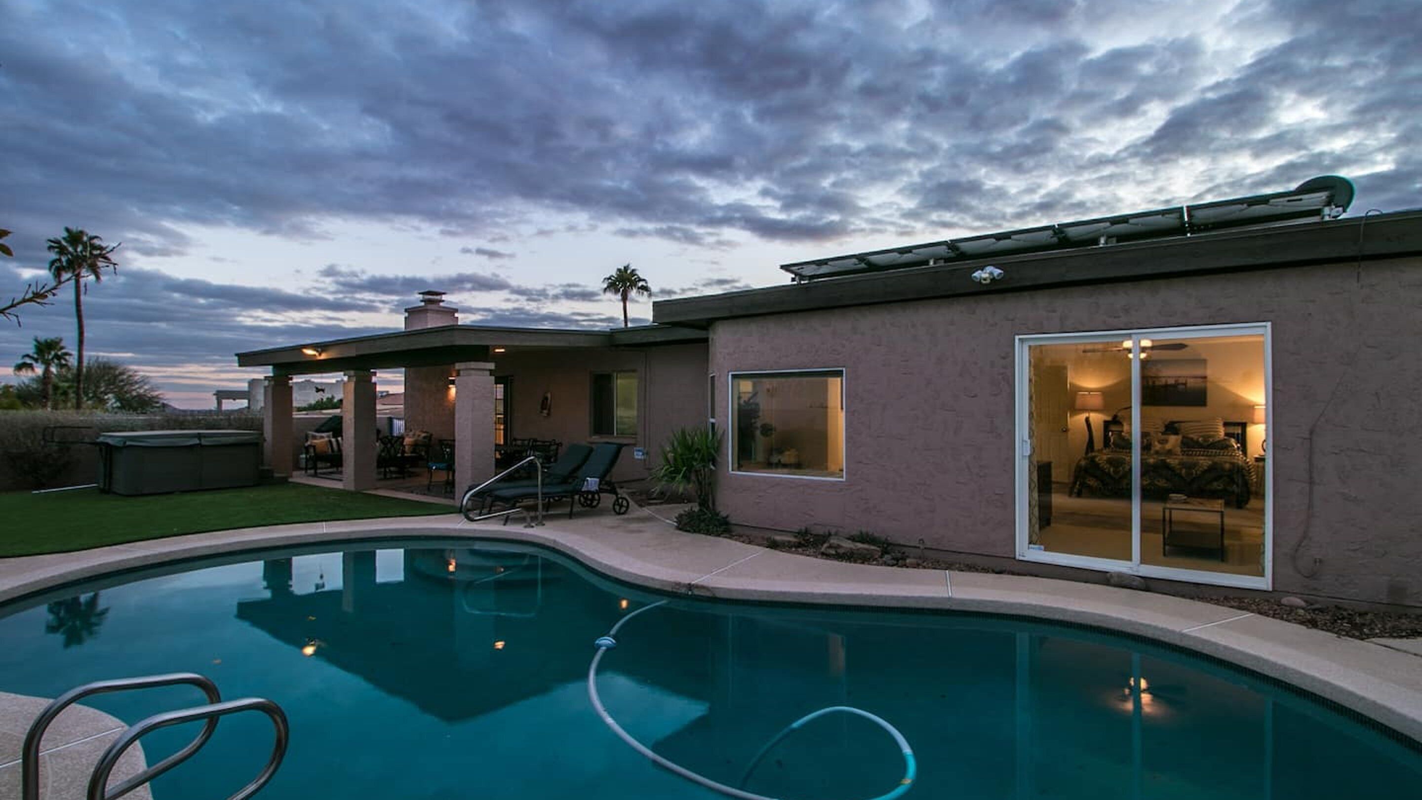 Una casa moderna con piscina, mobiliario de patio y una zona exterior cubierta.
