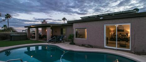 Una casa moderna con piscina, mobiliario de patio y una zona exterior cubierta.
