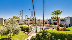 A modern hotel with multiple-story buildings, a swimming pool, and palm trees.