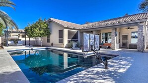Ett poolområde i ett bostadsområde med en klarblå pool, en basketkorg och en uteplats med utemöbler.