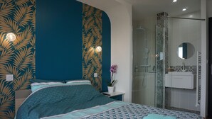 Ein Schlafzimmer mit einem Bett, einem Nachttisch, einer Topfpflanze und einem Badezimmer mit Dusche und Waschbecken.