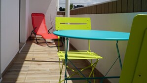 Ein Balkon mit Holzboden, einem Tisch und zwei Stühlen.