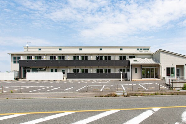 A modern building with a parking lot in front. - Tabist Hotel Takagiya Iwaki (Iwaki)