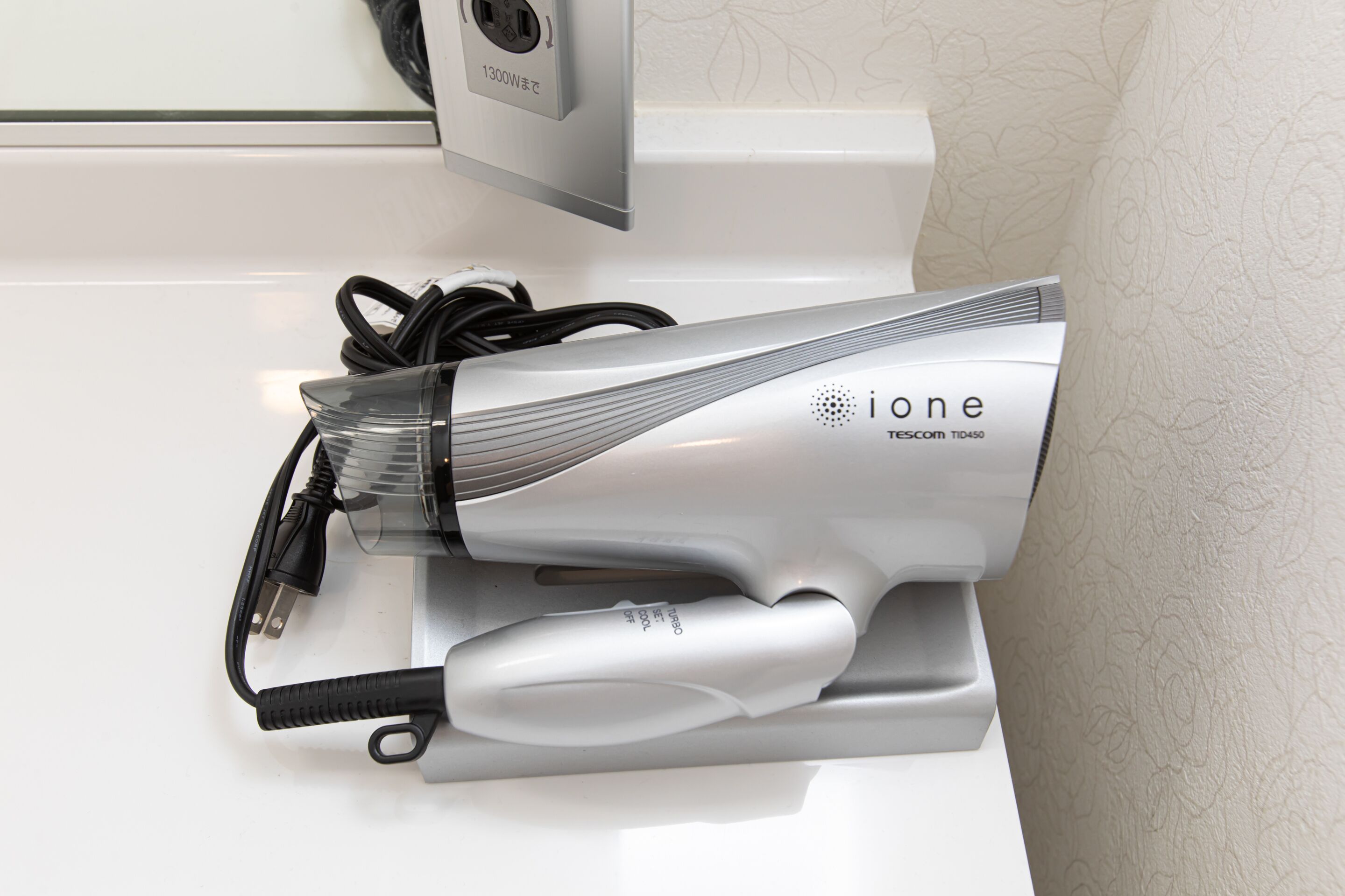 A hair dryer with a cord and a power adapter on a white surface.