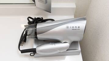 A hair dryer with a cord and a power adapter on a white surface.