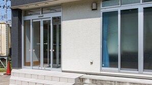 Un edificio con una entrada moderna que incluye puertas de vidrio y una serie de escalones que conducen a ella.
