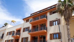 A multi-story building with balconies, a palm tree, and a clear sky. - APPARTAMENTO "FORGITELLA" 6 POSTI LETTO (Balestrate)