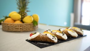 A table with pastries and a basket of fruits in the background. - APPARTAMENTO "FORGITELLA" 6 POSTI LETTO (Balestrate)