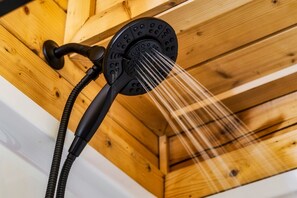 Un cabezal de ducha con múltiples chorros de agua en un techo de madera.
