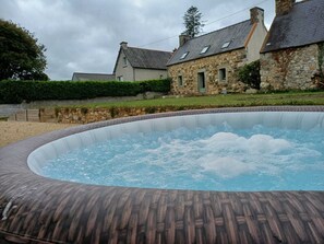 Un jacuzzi en un área ajardinada con edificios de piedra al fondo.