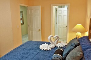 A hotel room with a bed, a nightstand, a lamp, and two doors.