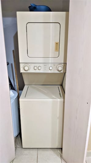 Ein kleiner, weißer Hauswirtschaftsraum mit einer gestapelten Waschmaschine und einem Trockner.