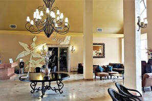 Eine großzügige Lobby mit rundem Tisch, einer Kristallleuchtre und einer Rezeption.