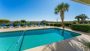 A swimming pool with clear blue water, surrounded by blue lounge chairs and palm trees. - Charming Ocean-view Condo at Ocean Pier 3 (North Myrtle Beach)