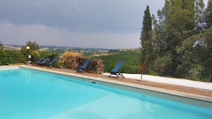 Piscina com espreguiçadeiras e vista para uma paisagem montanhosa.