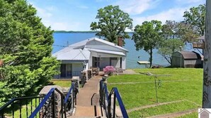Ein Haus mit einer Anlegestelle, die in einen See ragt, umgeben von Bäumen und einer Wiese.