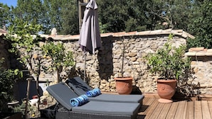 A wooden deck with a pool, lounge chairs, and potted plants.