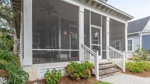 A house with a covered porch, a staircase, and a small garden area with plants. - Old Town Bluffton Home + FREE Golf Cart Luxury Home - Sleeps 8 (Bluffton)