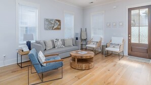 A modern living room with a grey sofa, blue armchair, and a wooden coffee table. - Old Town Bluffton Home + FREE Golf Cart Luxury Home - Sleeps 8 (Bluffton)