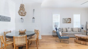 A dining area with a round table and wicker chairs, a living room with a sofa and armchairs, and a wooden coffee table. - Old Town Bluffton Home + FREE Golf Cart Luxury Home - Sleeps 8 (Bluffton)