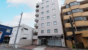 Un hôtel à plusieurs étages, avec une enseigne indiquant « HÔTEL DIANA » au niveau du rez-de-chaussée.