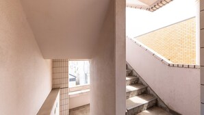 Un escalier avec un mur recouvert de carreaux, une fenêtre à motifs géométriques et un mur de briques en haut.