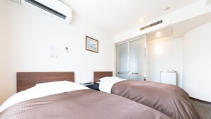 Une chambre d’hôtel avec deux lits, un bureau et un placard à portes coulissantes.