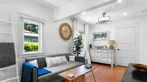 Een moderne woonkamer met een grijze bank, een houten salontafel en een groot raam met gordijnen.