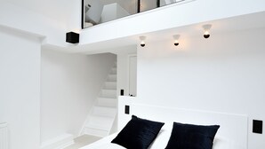 A modern bedroom with a large bed, a glass balcony, and a staircase. - Urban Walls (Brussels)