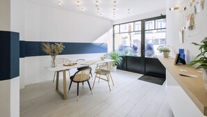 A modern dining area with a white table, gold chairs, and a blue accent wall. - Urban Walls (Brussels)