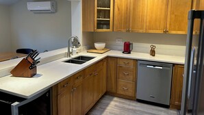 A modern kitchen with wooden cabinets, a stainless steel dishwasher, and a built-in oven.